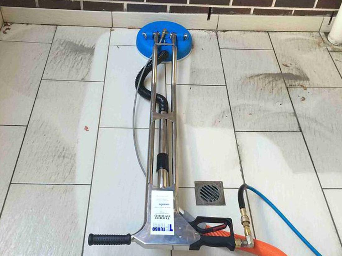Rotary tile and grout cleaning head working across a tiled floor